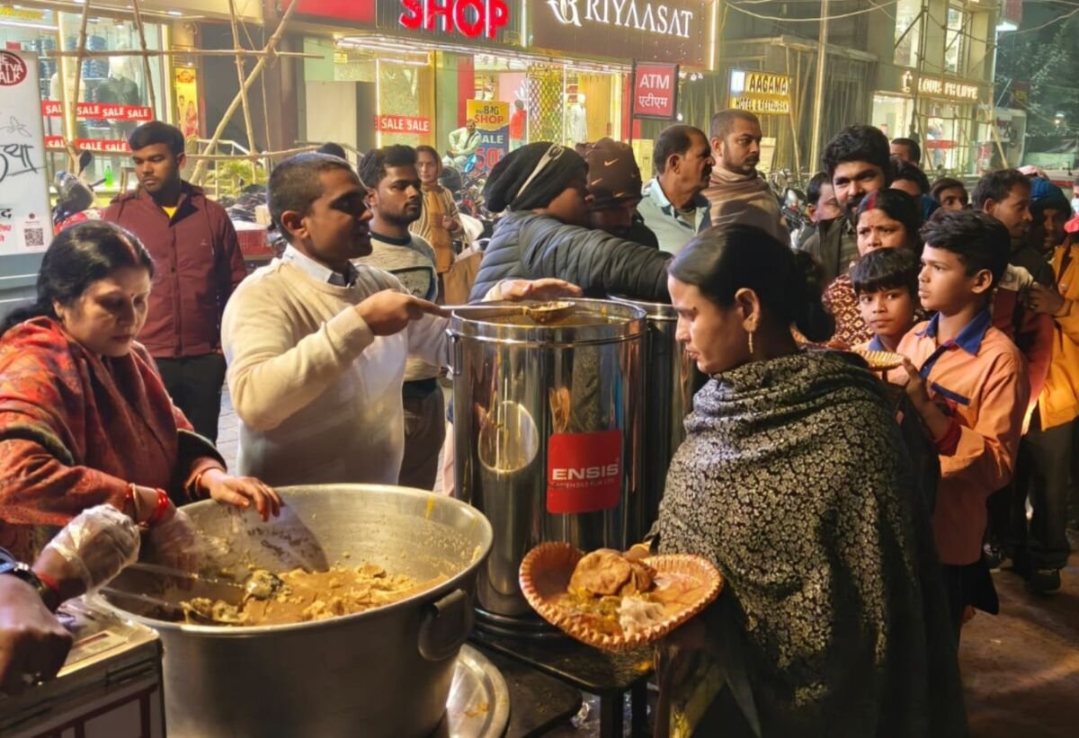 Devotees serving hot prasadam from large pots to people in need